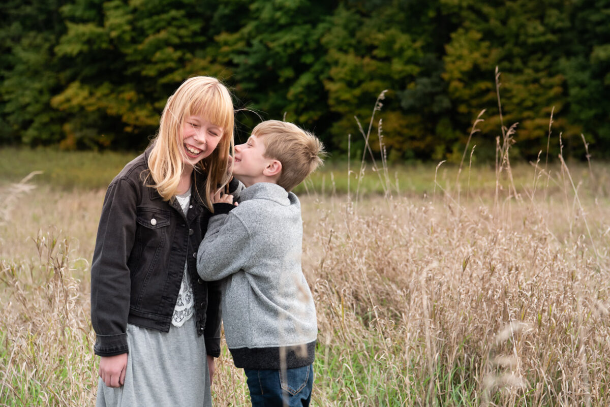 Boy whispering to sister. Livonia photographer near me